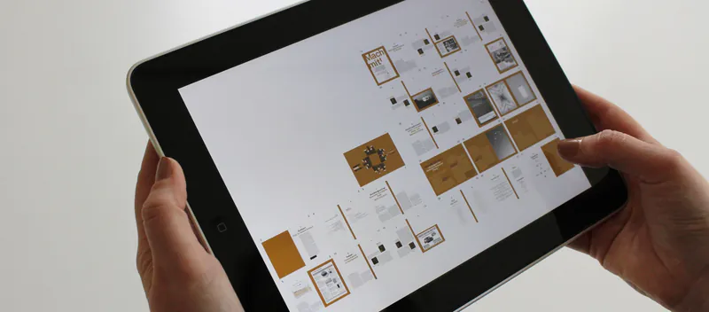 Hands holding a tablet showing a grid of page layouts